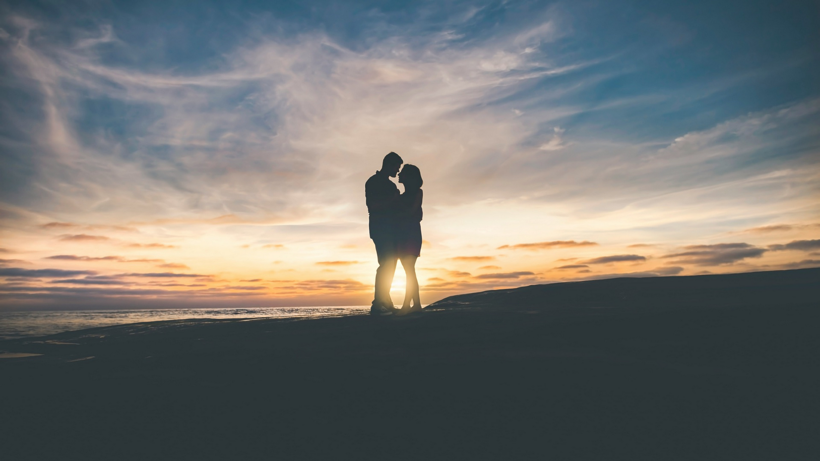 Silhouetted couple under a warm sunset.