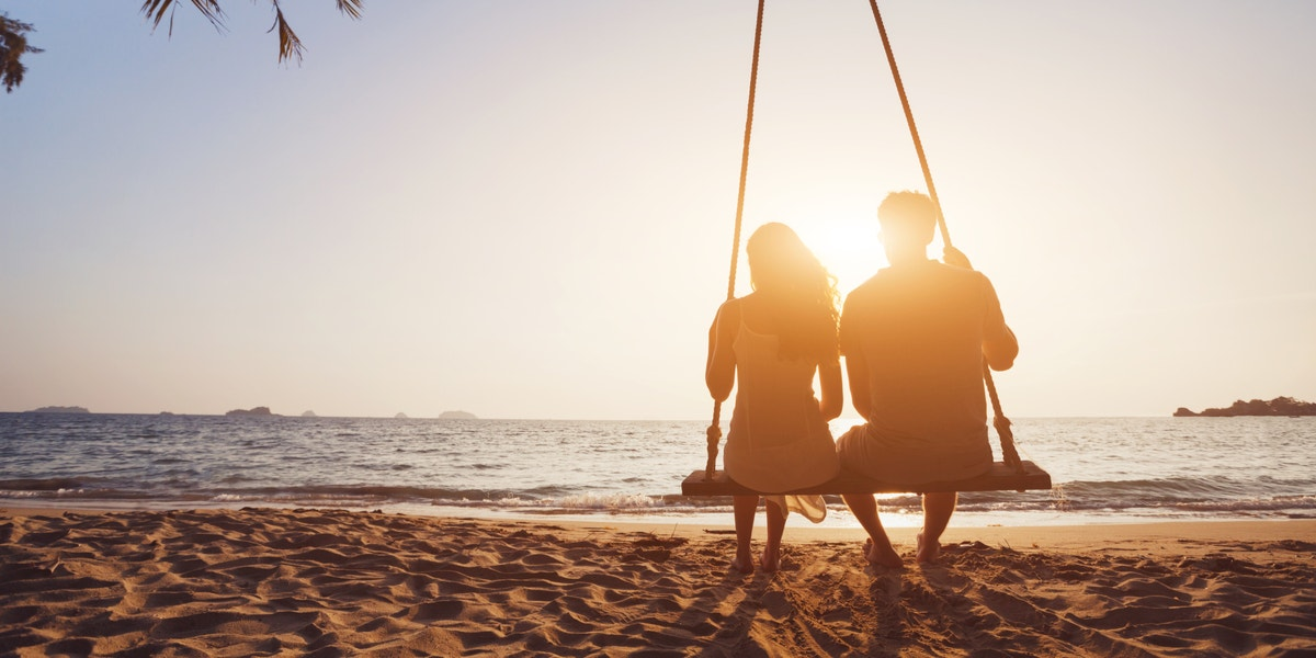 A couple swinging together at sunset.